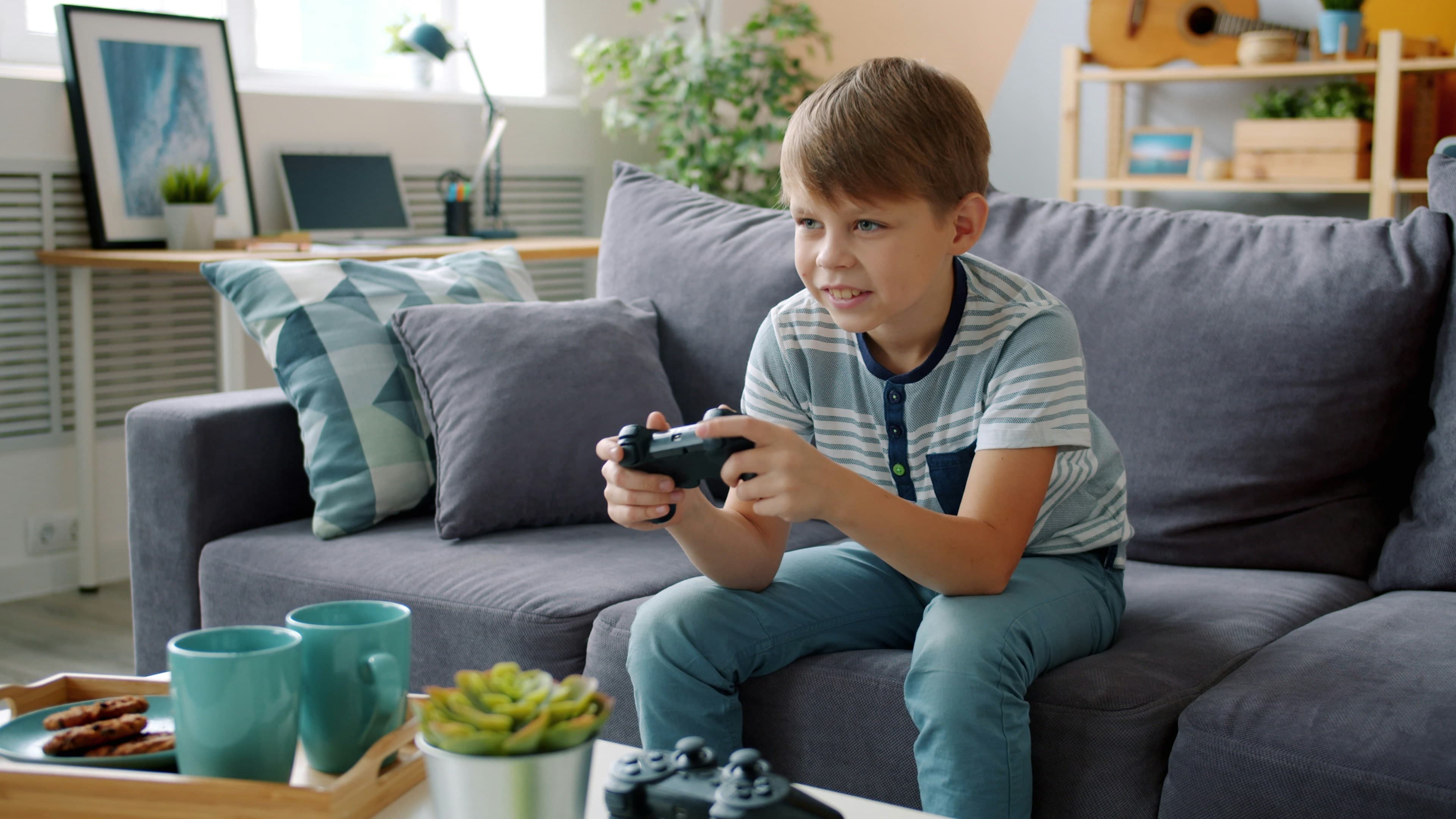 ソファでゲームコントローラーを持つ子ども
